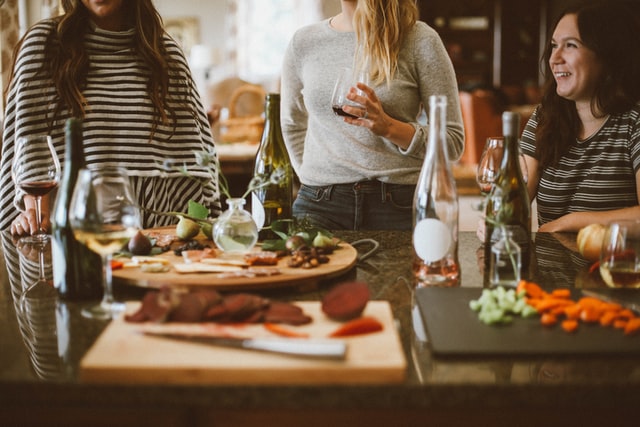 Three people drinking wine in a kitchen