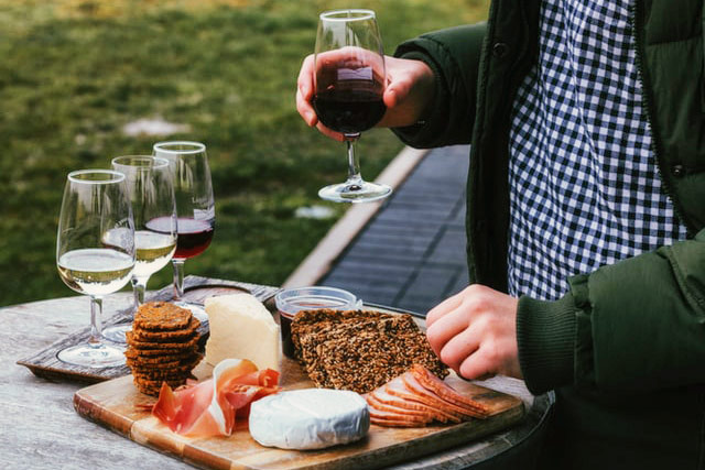 One person samples wine near an appetizer platter and other glasses of wine